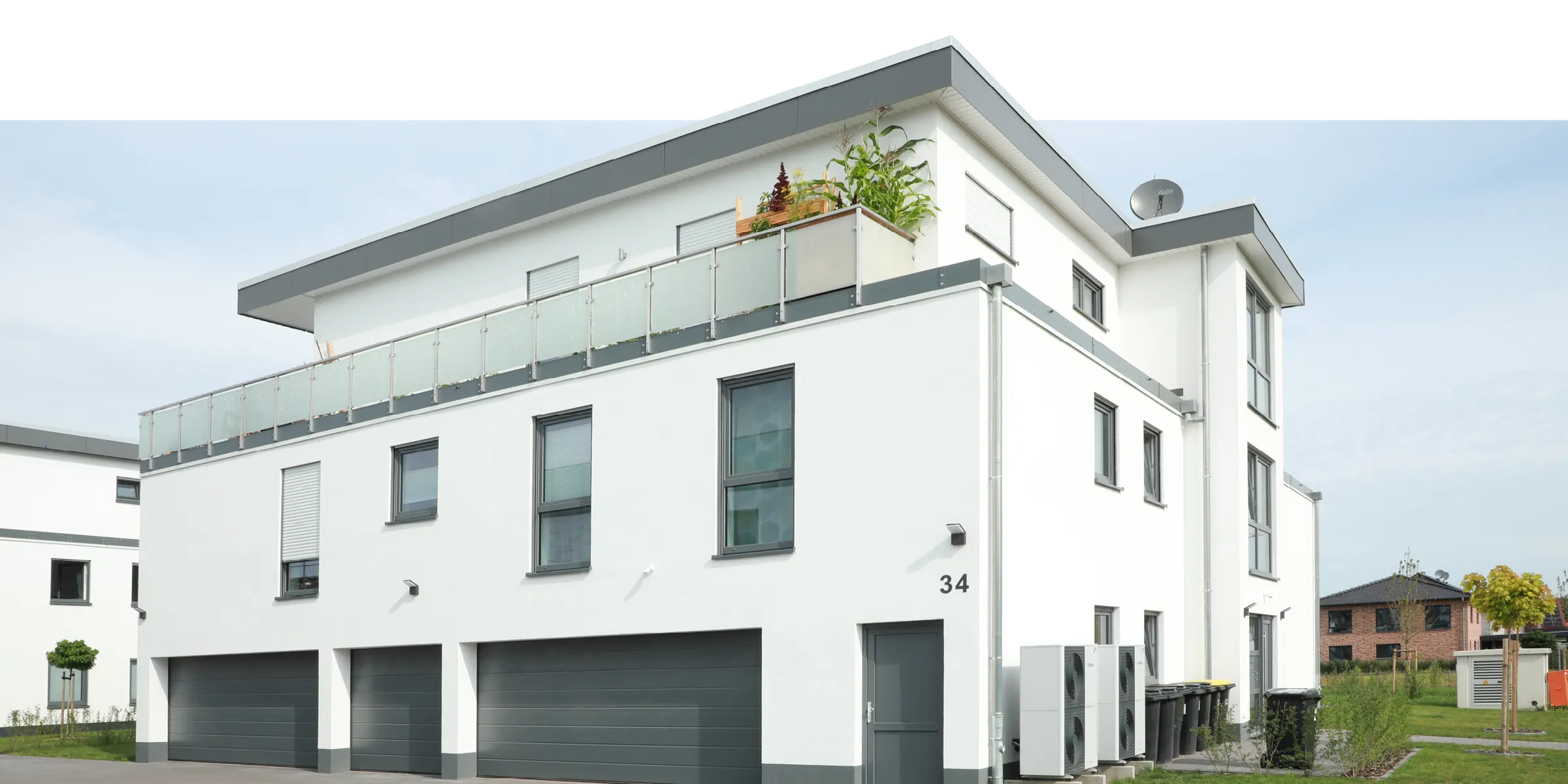 Weißes Mehrfamilienhaus mit Staffelgeschoss und Garagen – gebaut von DENKER Eigenheim